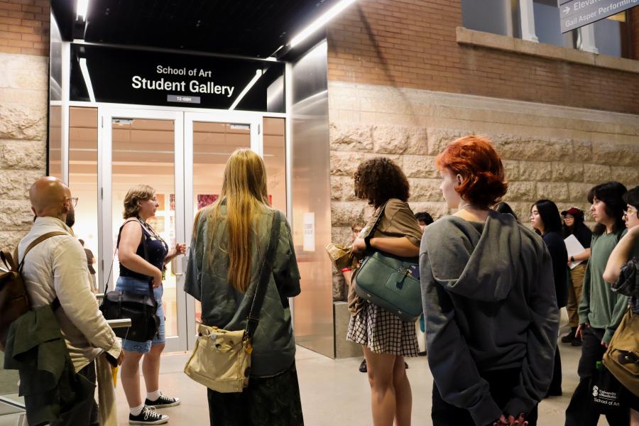 A group gathers outside the School of Art Student Gallery during an evening event.