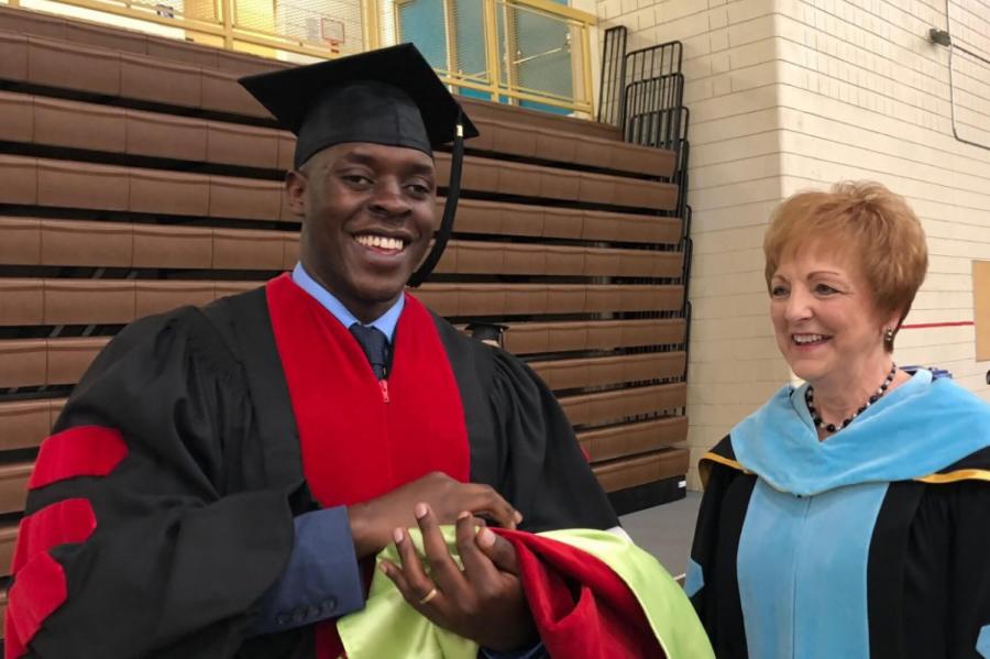 A Nursing PhD student stands for a photo during graduation.