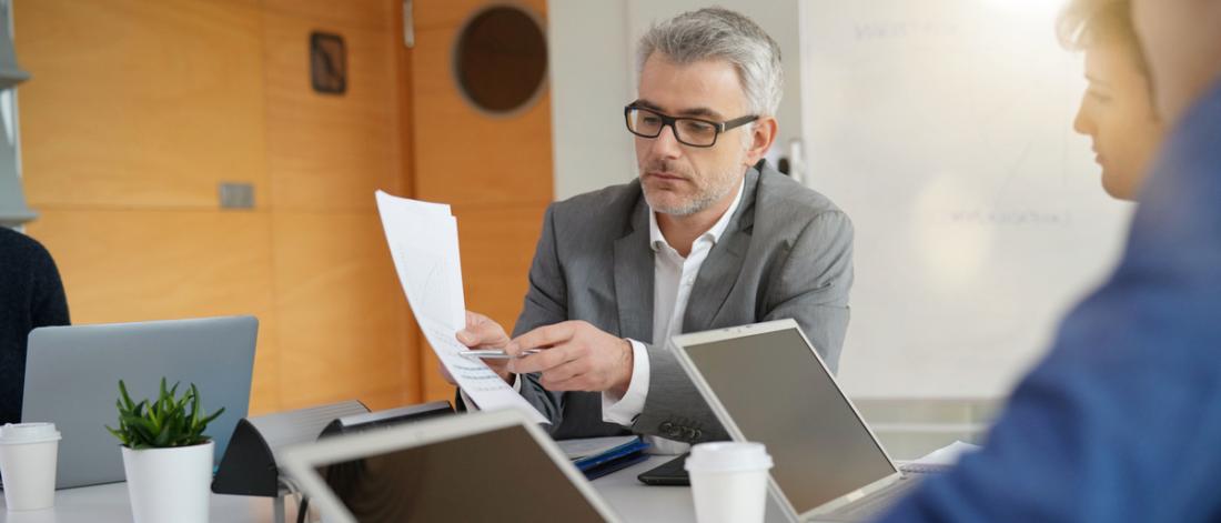 middle aged manager presents report to two colleagues