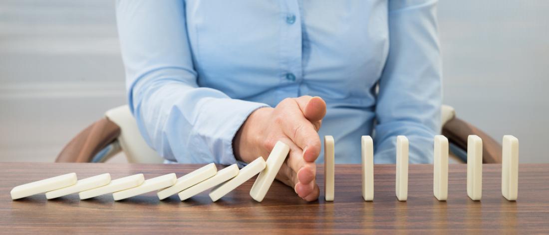 Hand stopping dominos on a table