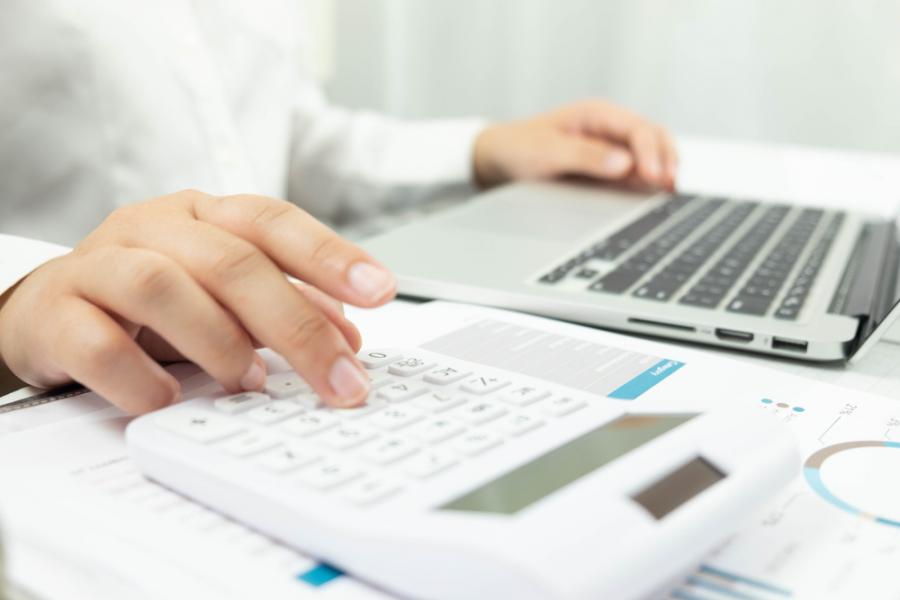 hands working on calculator and laptop