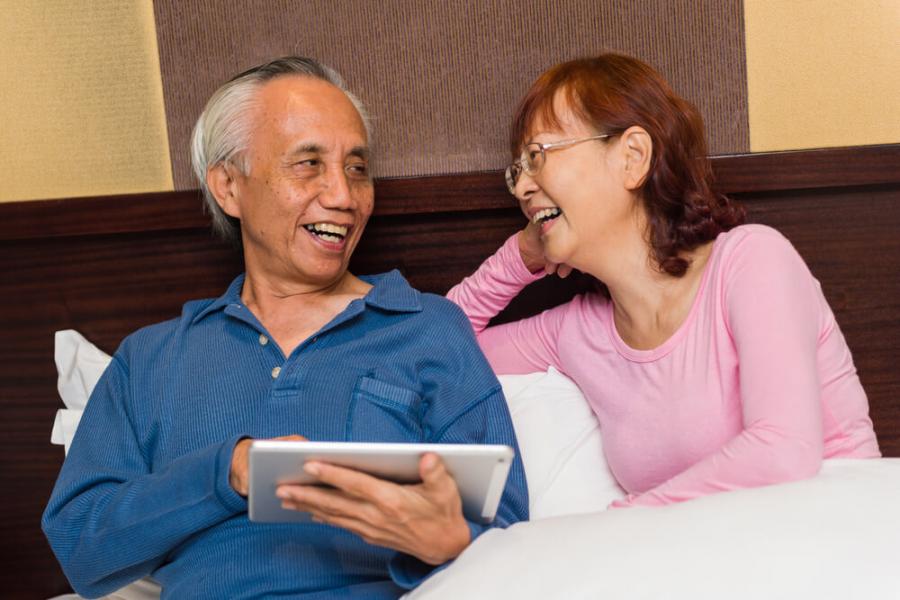 Asian senior couple laughing and enjoying learning new technology