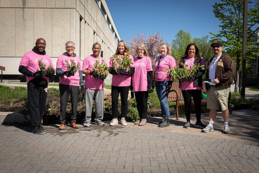 University leadership standing in a line holding plants.