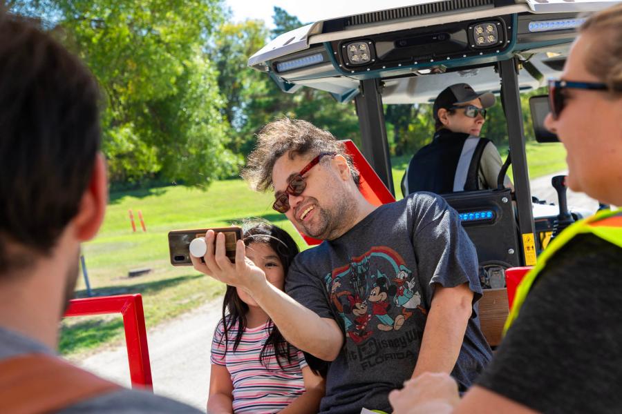 2 visitors take a picture as they ride in the trailer