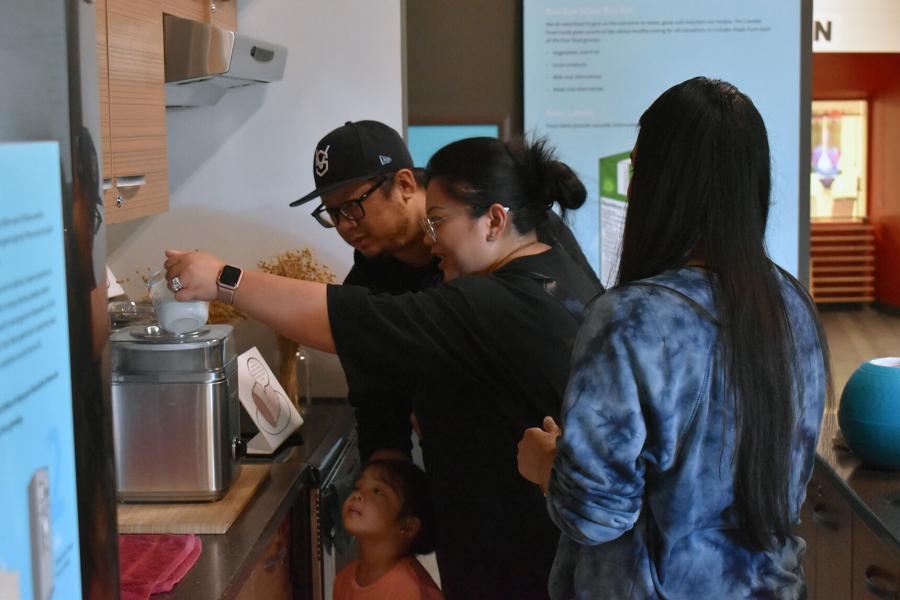 A family experiments with a display as a volunteer looks on