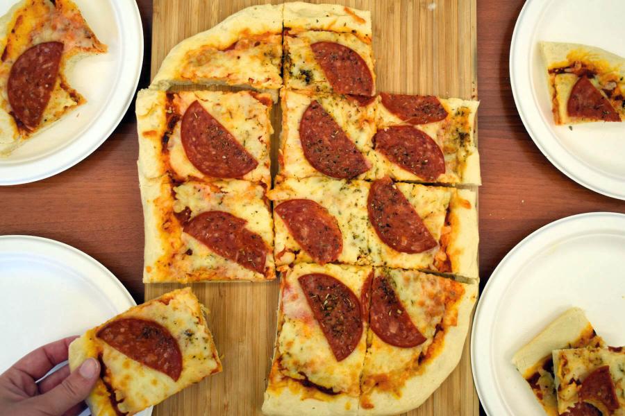 A person takes a slice of pizza on display