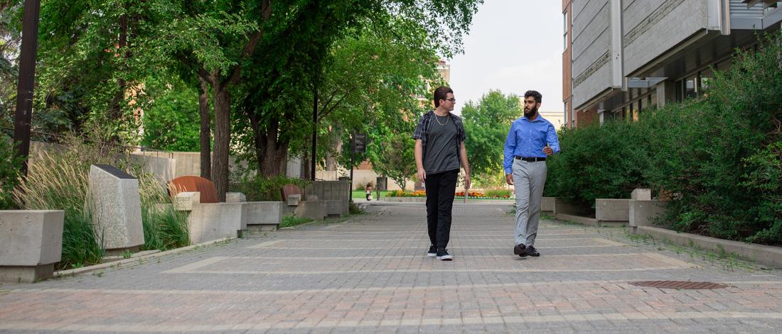 two students walking outside in summer at fort garry campus