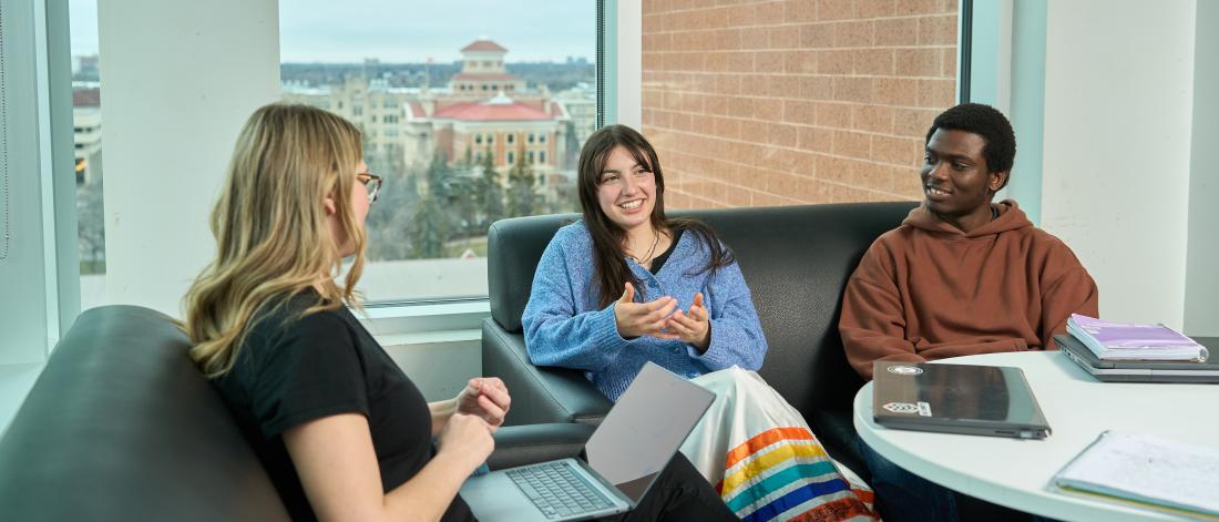 three students sitting on couches and chatting