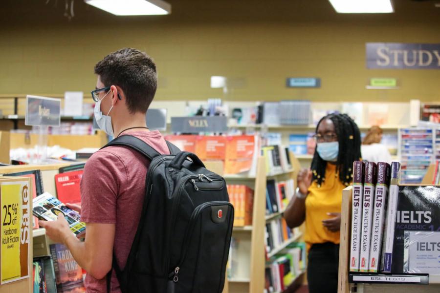 Two students looking at books inside the bookstore.