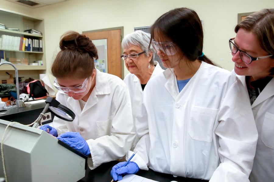 Students in lab coats participate in the Verna J. Kirkness program.