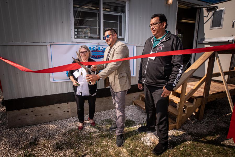 A man and women stand beside a man cutting a red ribbon in front of the EleV Learning Hub.
