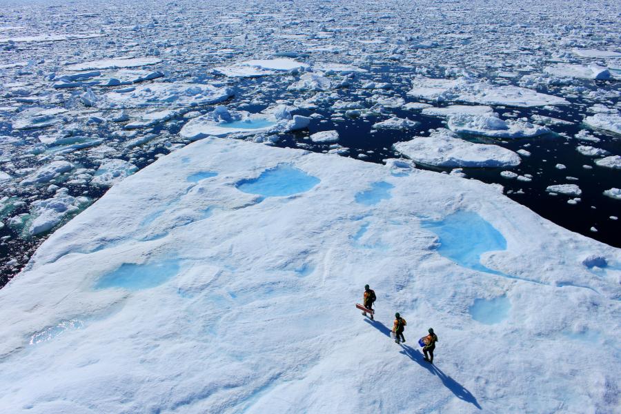 three researcher walk across a ie sheet in artic waters