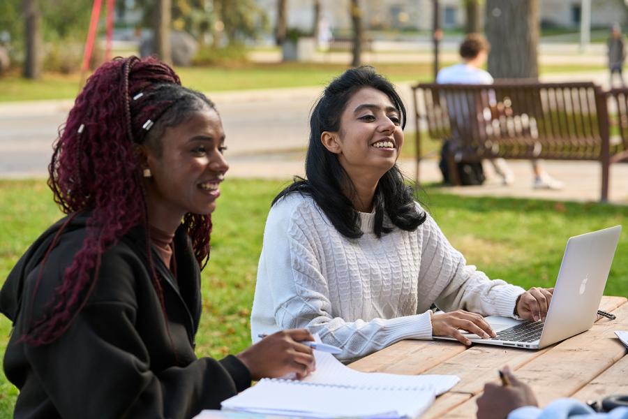 two girls chatting at a picnic table outside
