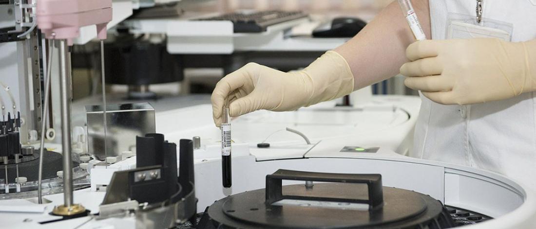 A researcher placing a blood sample into a spinner machine.