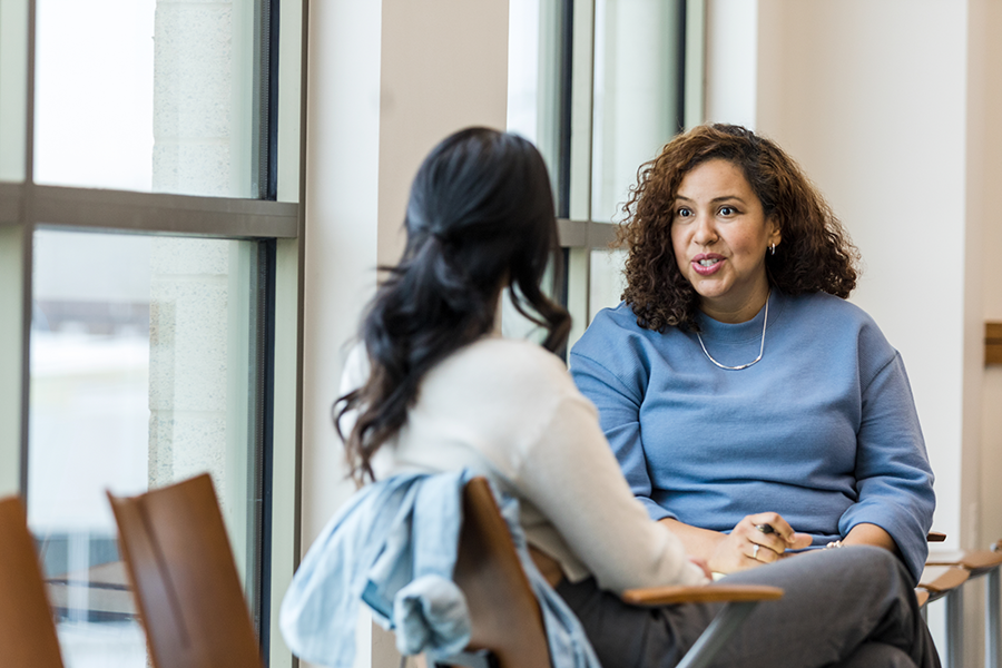 Two people sitting in a corridor, having a conversation.