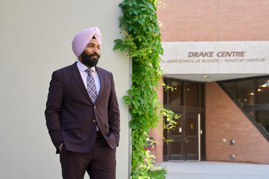 Man in suit standing outside the Asper School of Business Drake Centre during the summer.