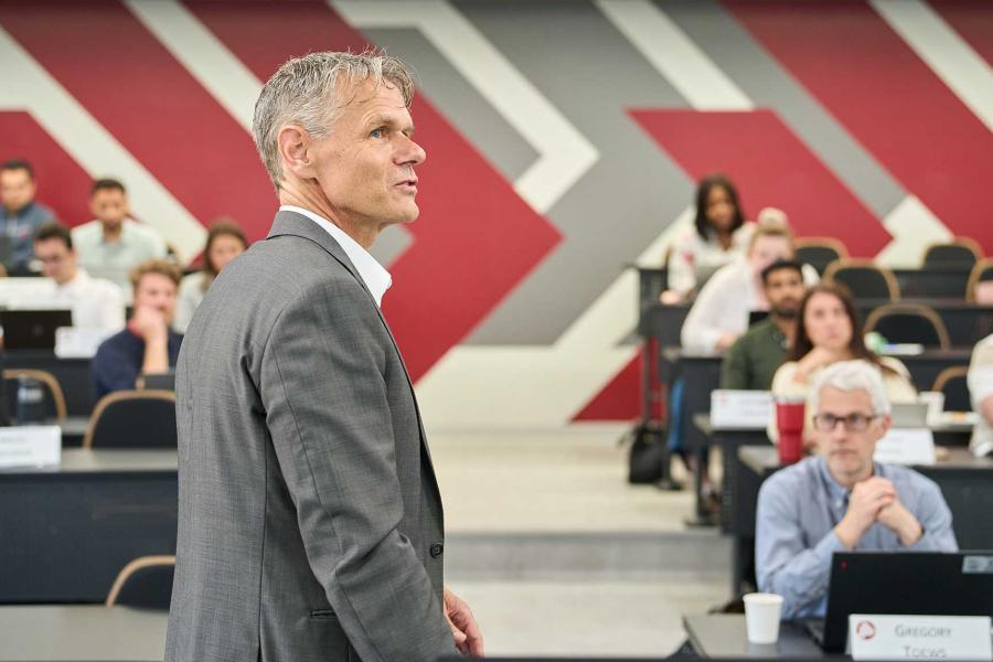 Male professor talking to a room of students at the Asper School of Business.