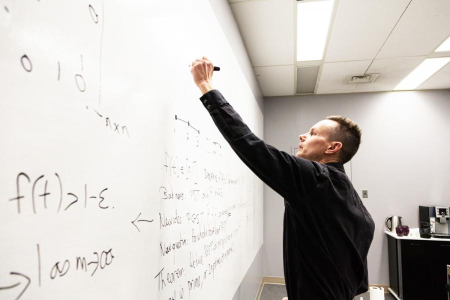 Man writing an equation on a whiteboard.