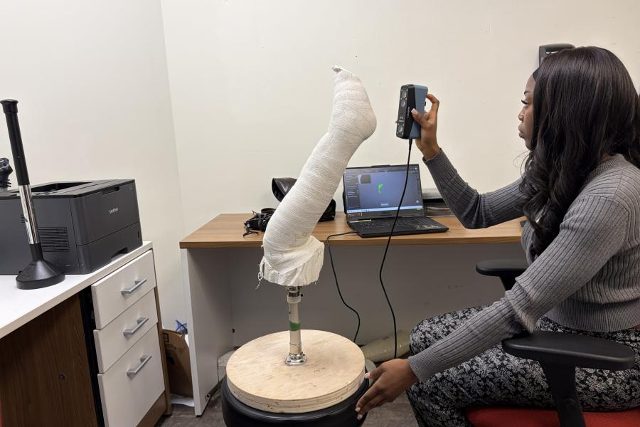 Student in an office using a computer hooked up to an orthopedic limb.