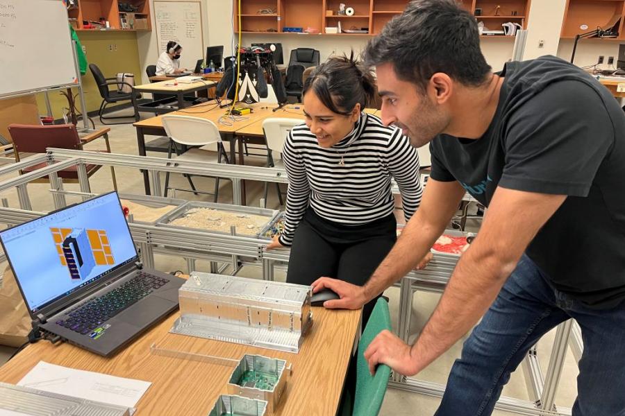 Two mechanical engineering students looking at a computer showing rendering in a lab.