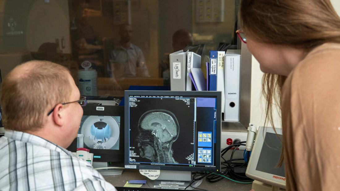 Two researchers review and discuss a brain imaging scan.