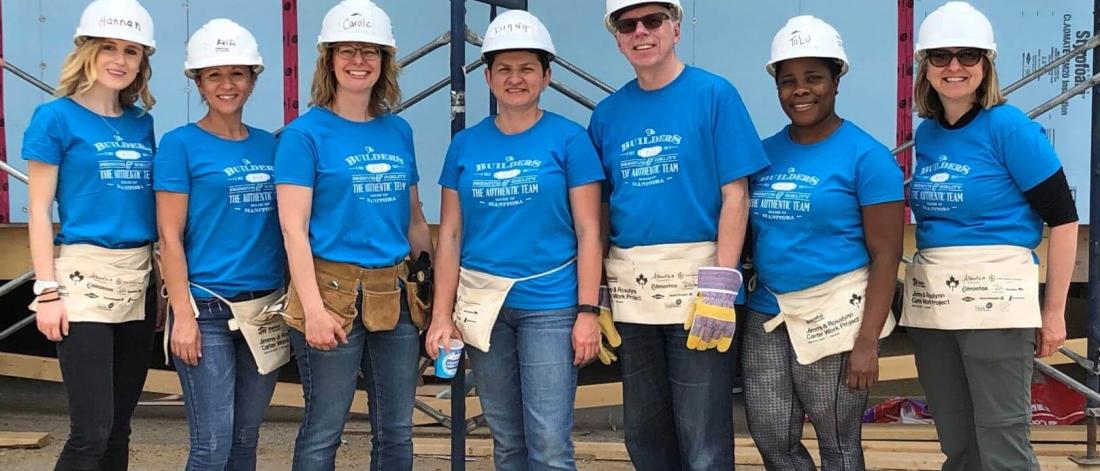 Staff wearing blue Habitat for Humanity t-shirts in front of a construction site.