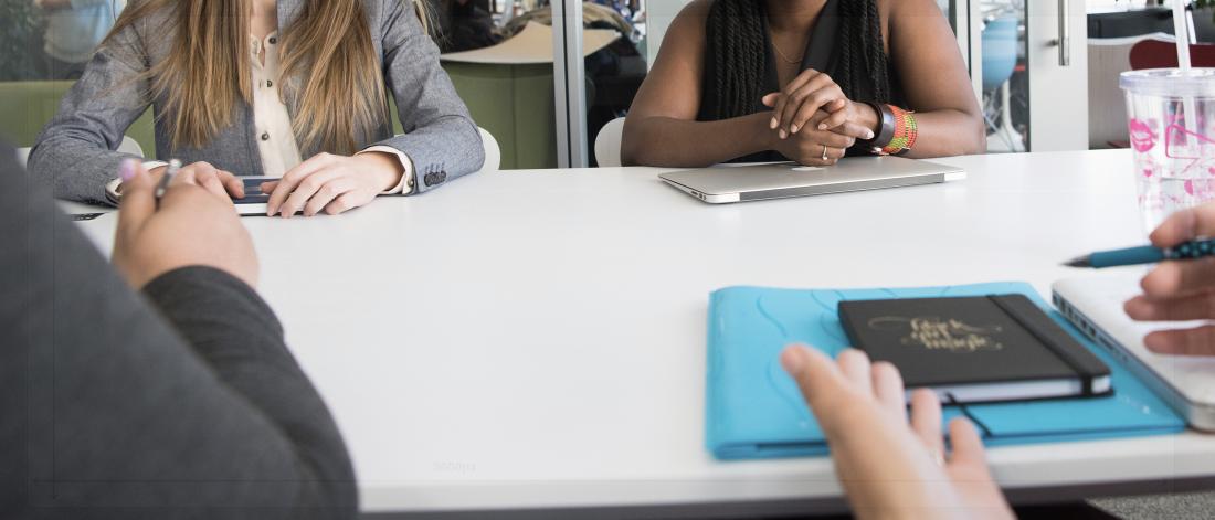 A group of people sitting around a table in a boardroom setting.