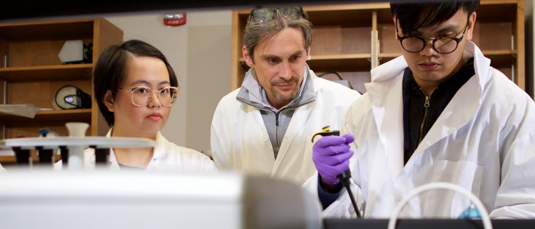 Professor watching students fill test tubes.