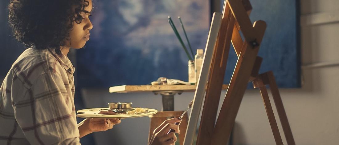 Woman painting at an easel.