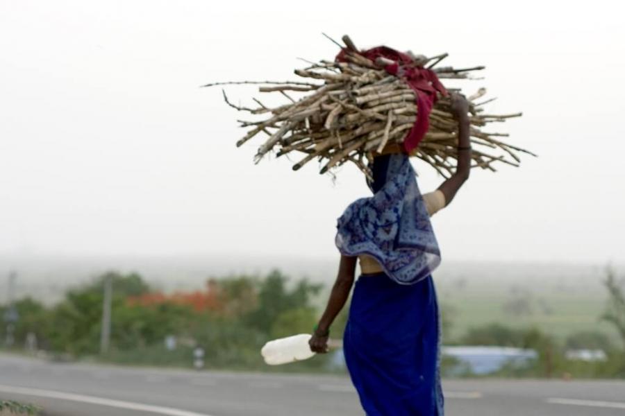 Woman carries a bundle of sticks on her head