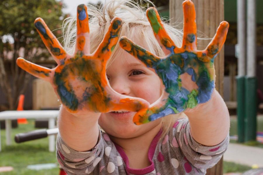 Child displays messy hands after finger painting