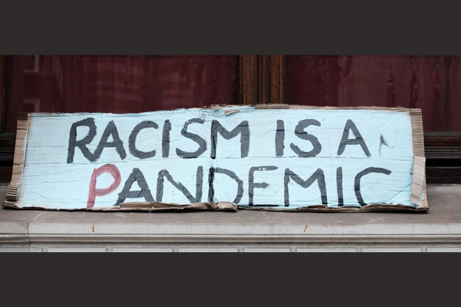 Hand written sign reading "racism is a pandemic."