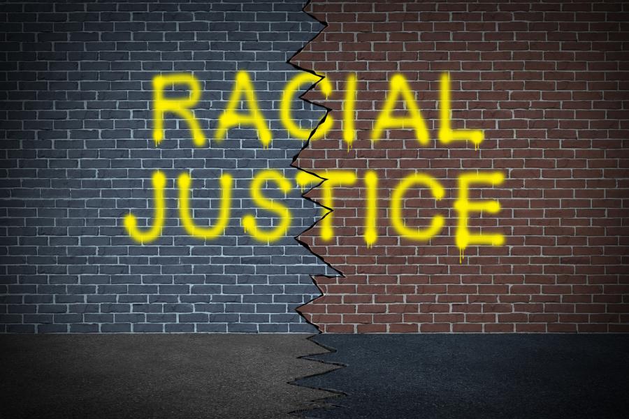 Graffiti spray-painted on a brick wall reading "racial justice."