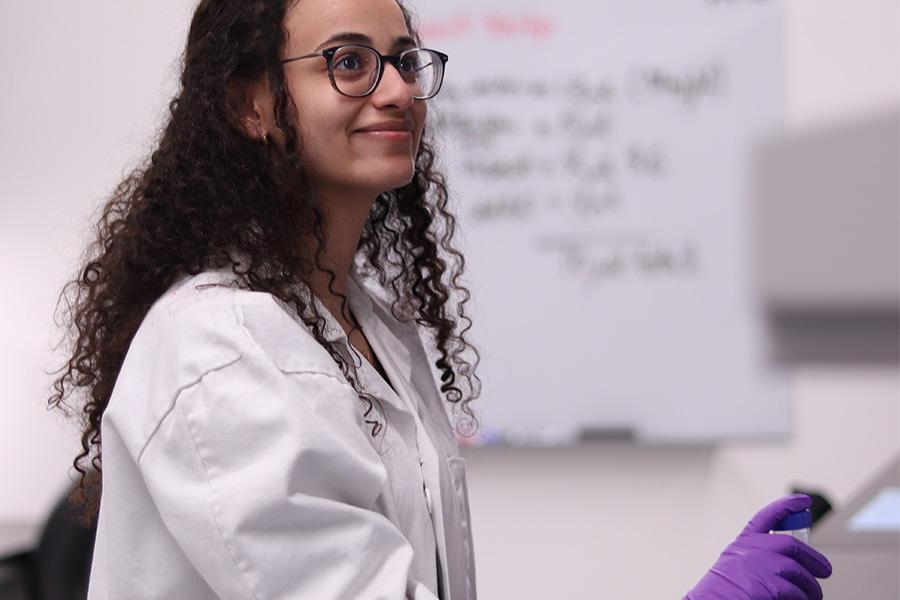 A person in a lab coat holding a sample.