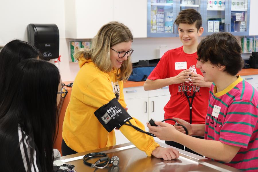 A student is checking another students blood pressure with a blood pressure cuff.