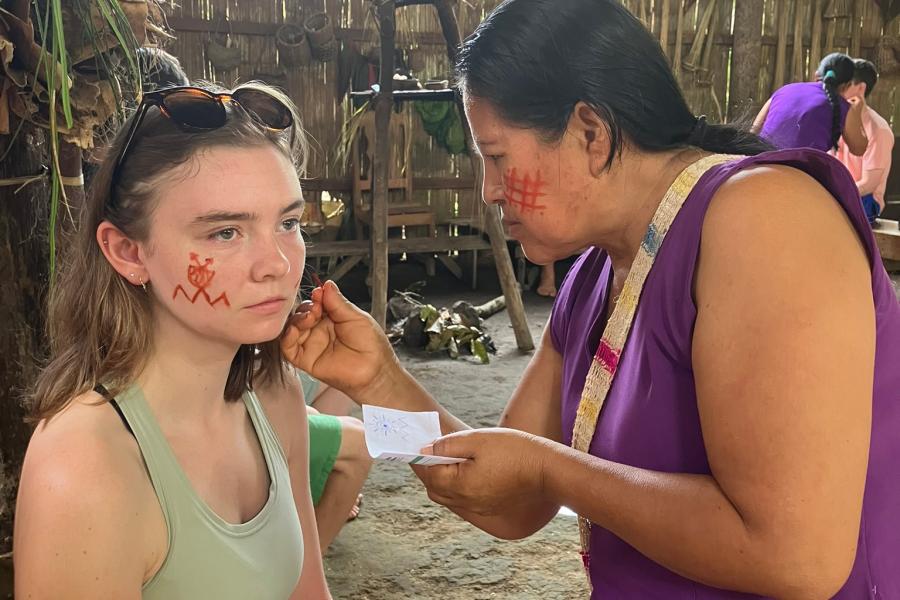 A student gets their face painted by an local community member.
