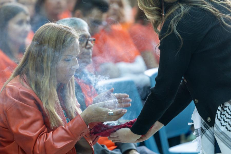 A person cleanses themself with smudge smoke.