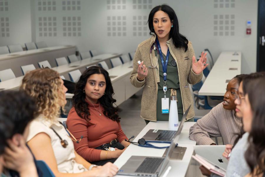 An instructor speaks to a group of students in a classroom.