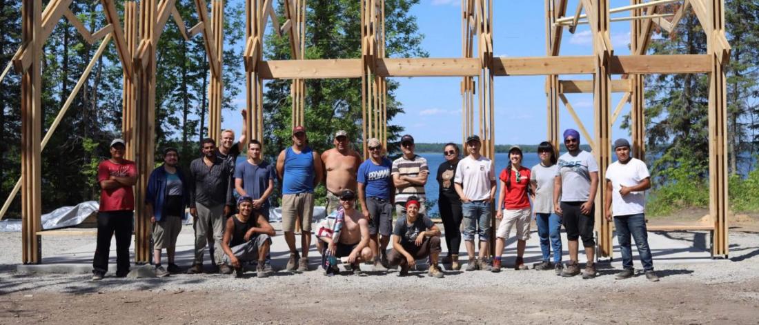 Members of the Engineering and Architecture faculties stand together in front of a ceremonial structure they have built at Shoal Lake 40. 