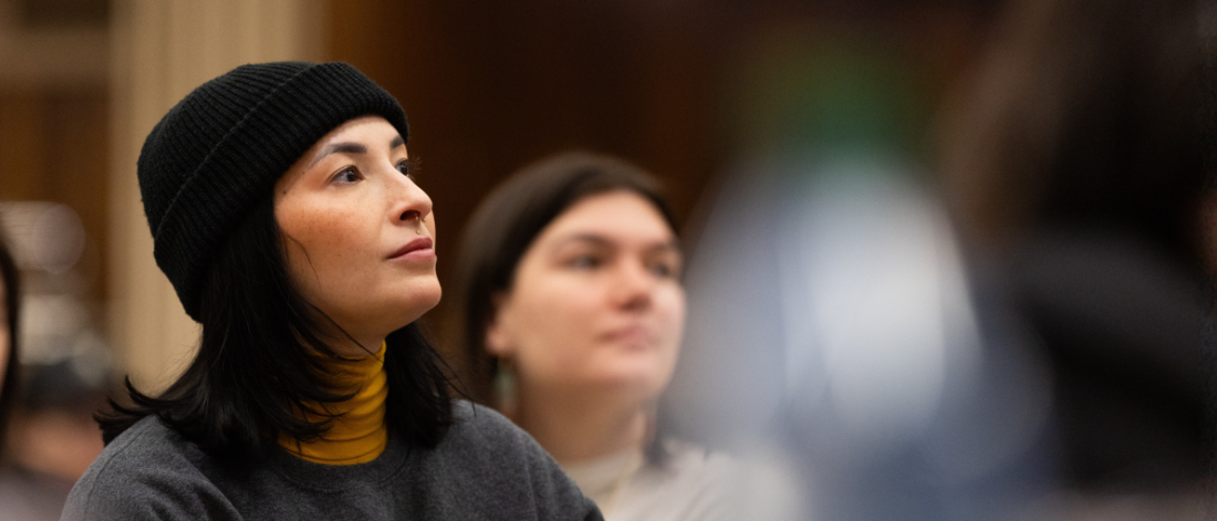Woman in black beanie attentively listening at a gathering.