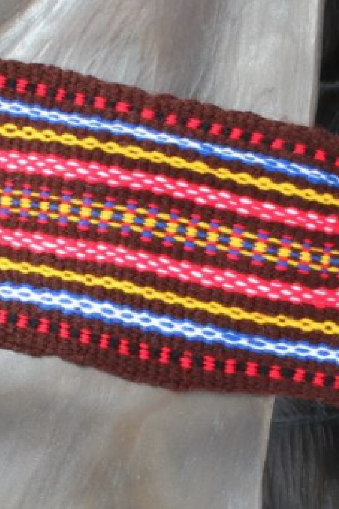 A colourful Métis woven sash tied around a statue’s waist.