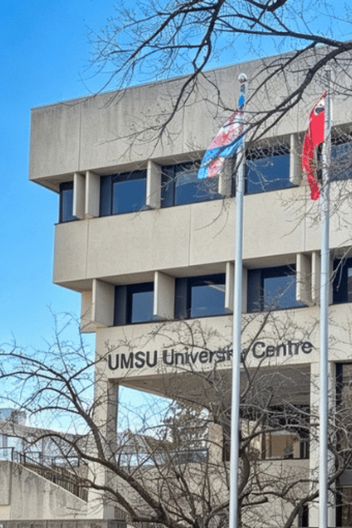 UMSU University Centre on the University of Manitoba campus with flags in front.