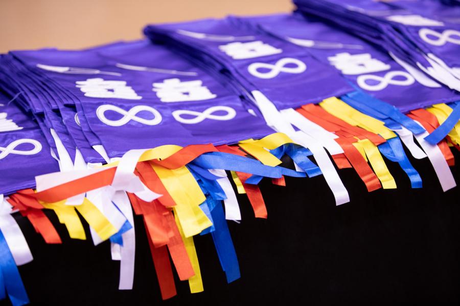 A table full of folded purple indigenous graduation scarfs. 