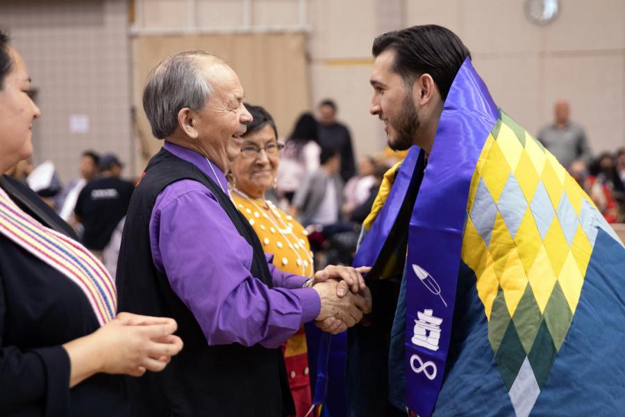 A student receives his Indigenous scarf at the graduation PowWow.