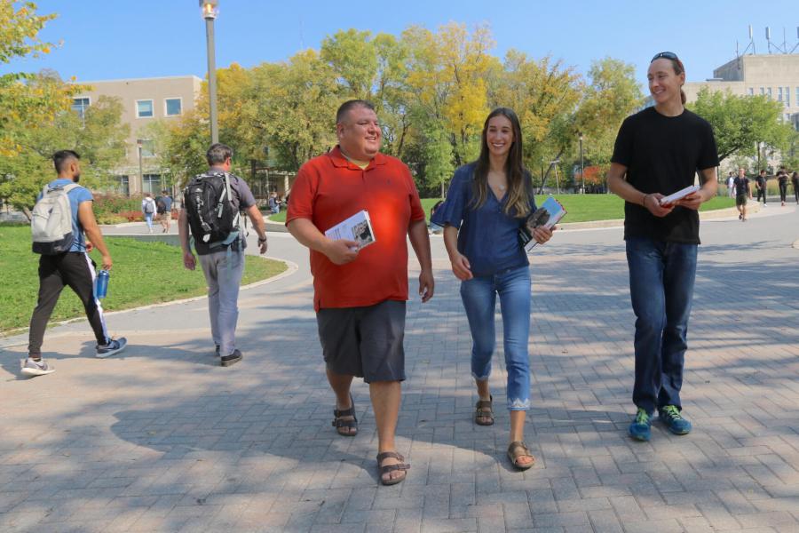 Three people walking together along Curry Place at the University of Manitoba Fort Garry campus. 