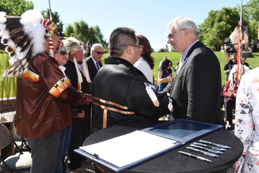 President Barnard signs the City of Winnipeg Indigenous Accord on behalf of the University of Manitoba during the Oodena Celebration Circle at The Forks.