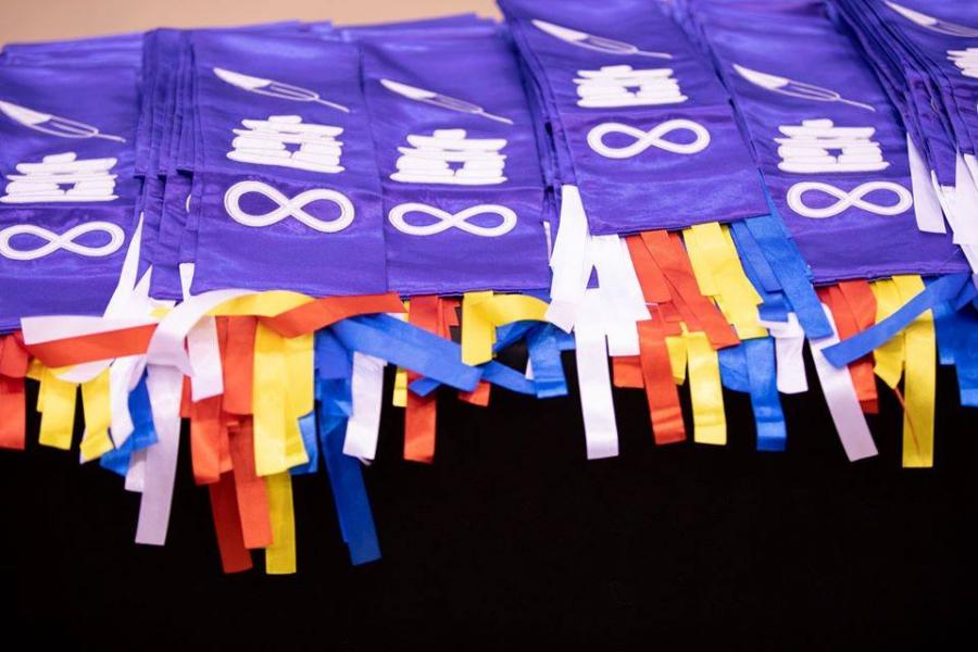 A folded pile of purple Indigenous graduation stoles