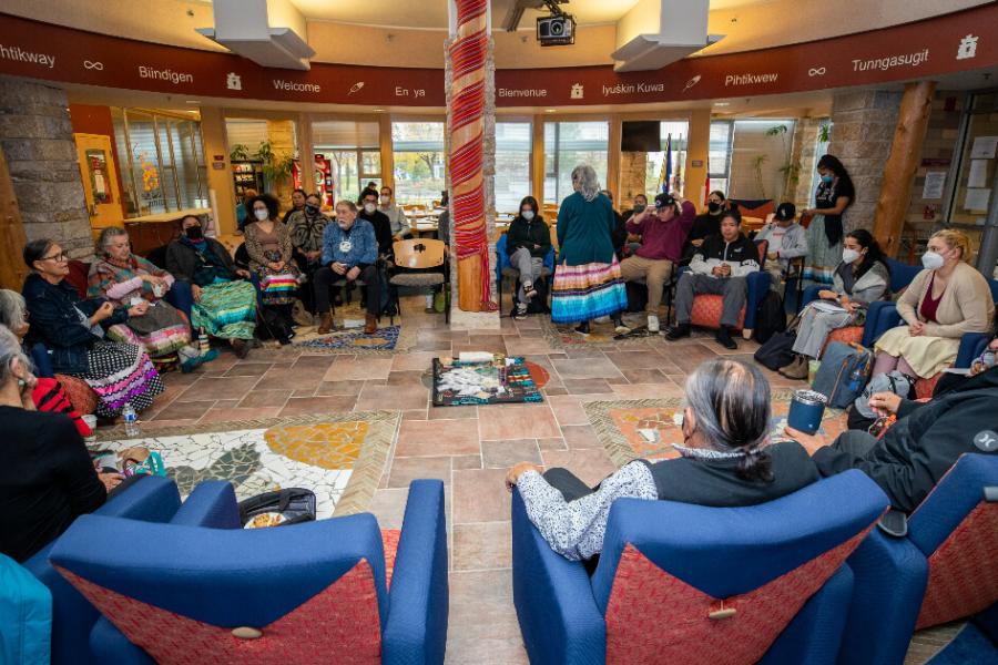 A group of Indigenous Elders sitting in a circle, surrounding a collection of traditional medicines.