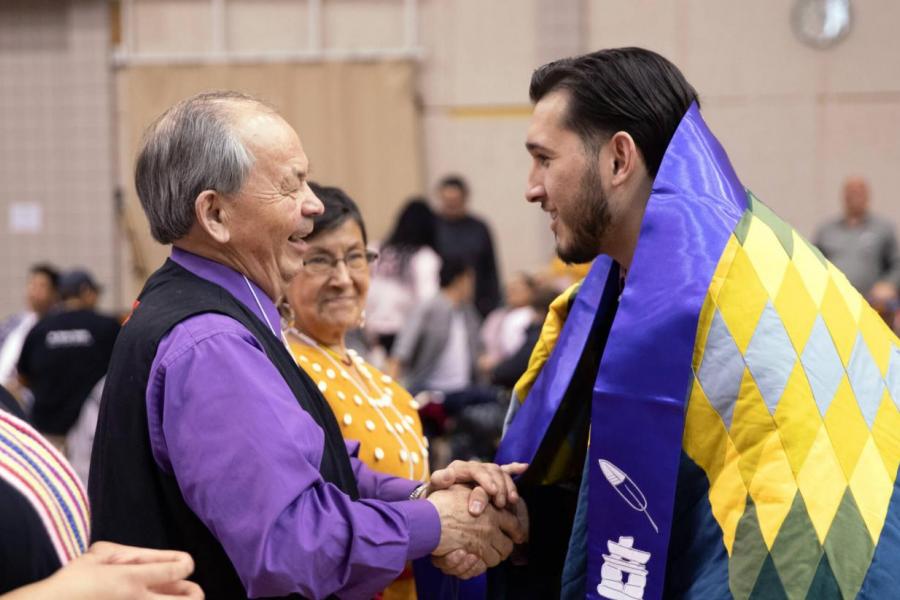 A student receiving their graduation stole at the graduation pow wow.
