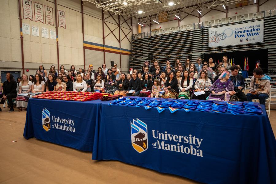 graduates seated at pow wow with stoles and sashes on display
